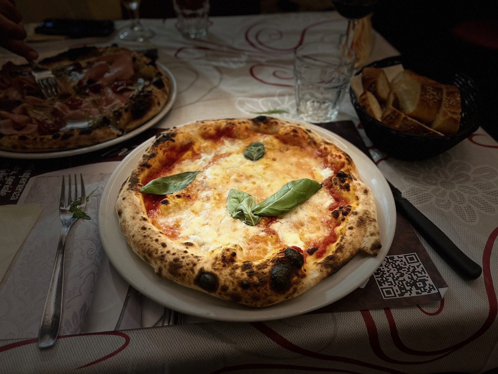 Pizza topped with basil leaves on a plate.