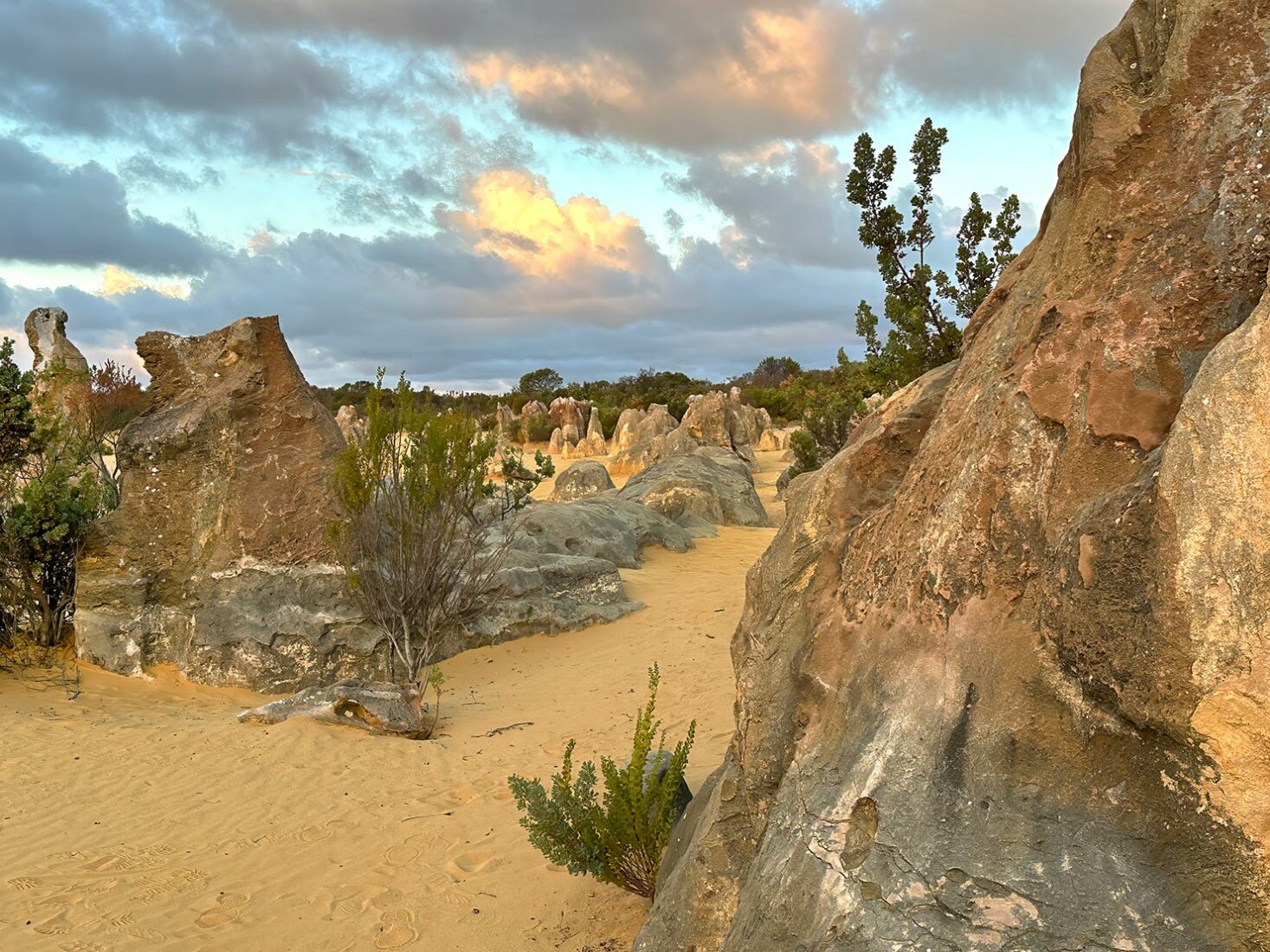 The sun begins to set in the late afternoon, painting the sand and rock formations in richer hues