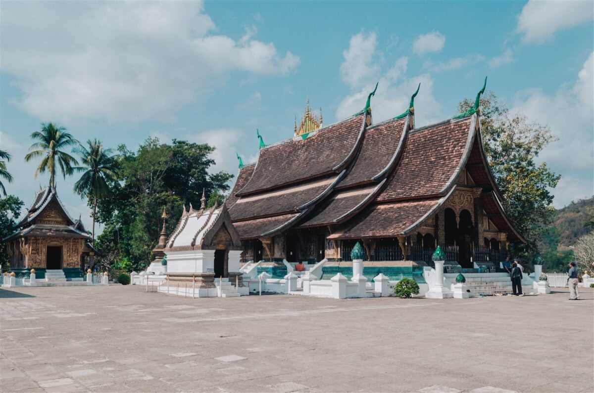 Beautiful Buddhist temples in Luang Prabang, Laos, showcasing traditional architecture with ornate details and lush greenery in the background.