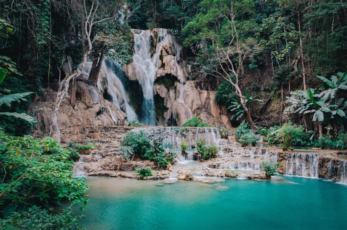 Stunning Kuang Si Waterfalls in Luang Prabang, Laos, with cascading turquoise water surrounded by lush green foliage, offering a serene and picturesque spot for solo travelers.