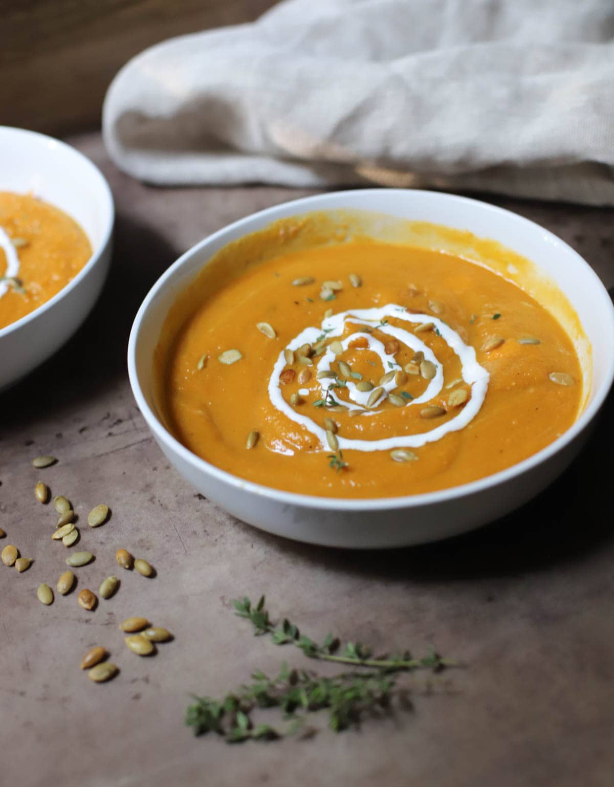 Butternut squash soup topped with sour cream and pepitas in a bowl.