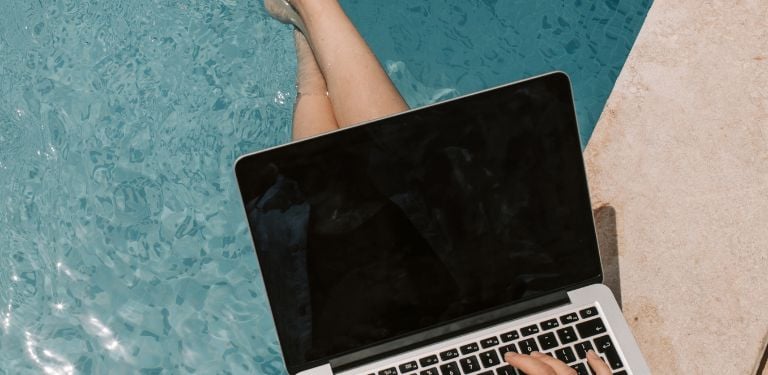 Digital nomad working on a laptop by the pool