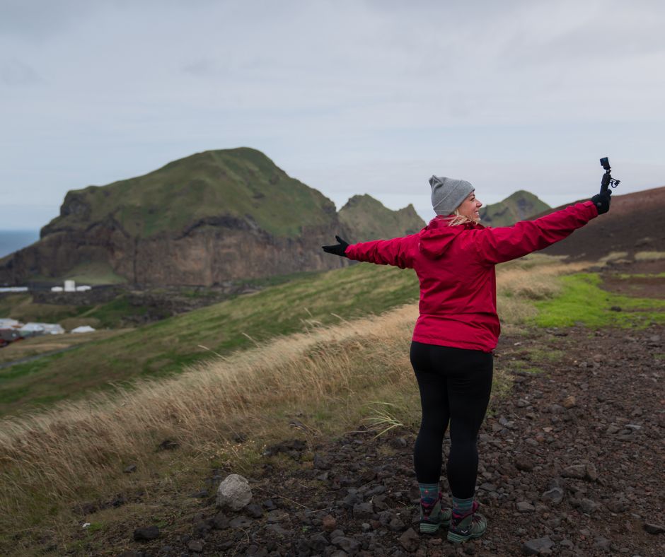 Jeannie filming with a camera while wearing rain gear for Iceland | Iceland with a View