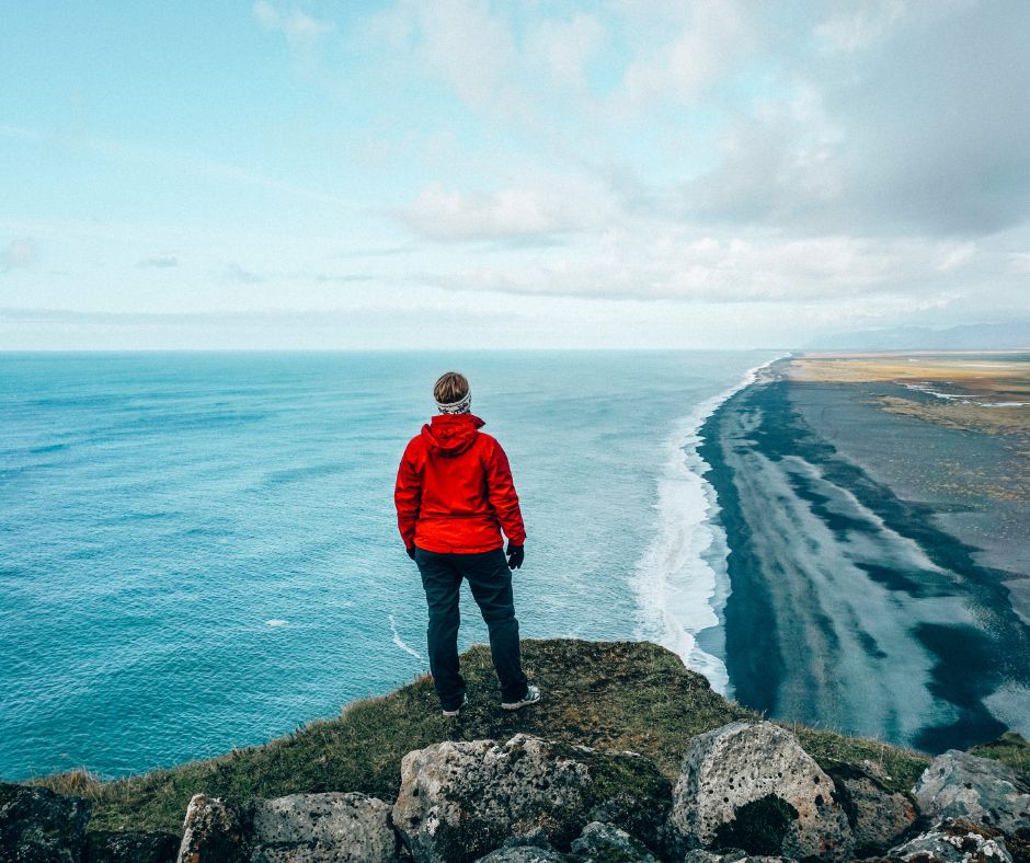 Jeannie sightseeing Dyrholaey while wearing rain gear for Iceland | Iceland with a View