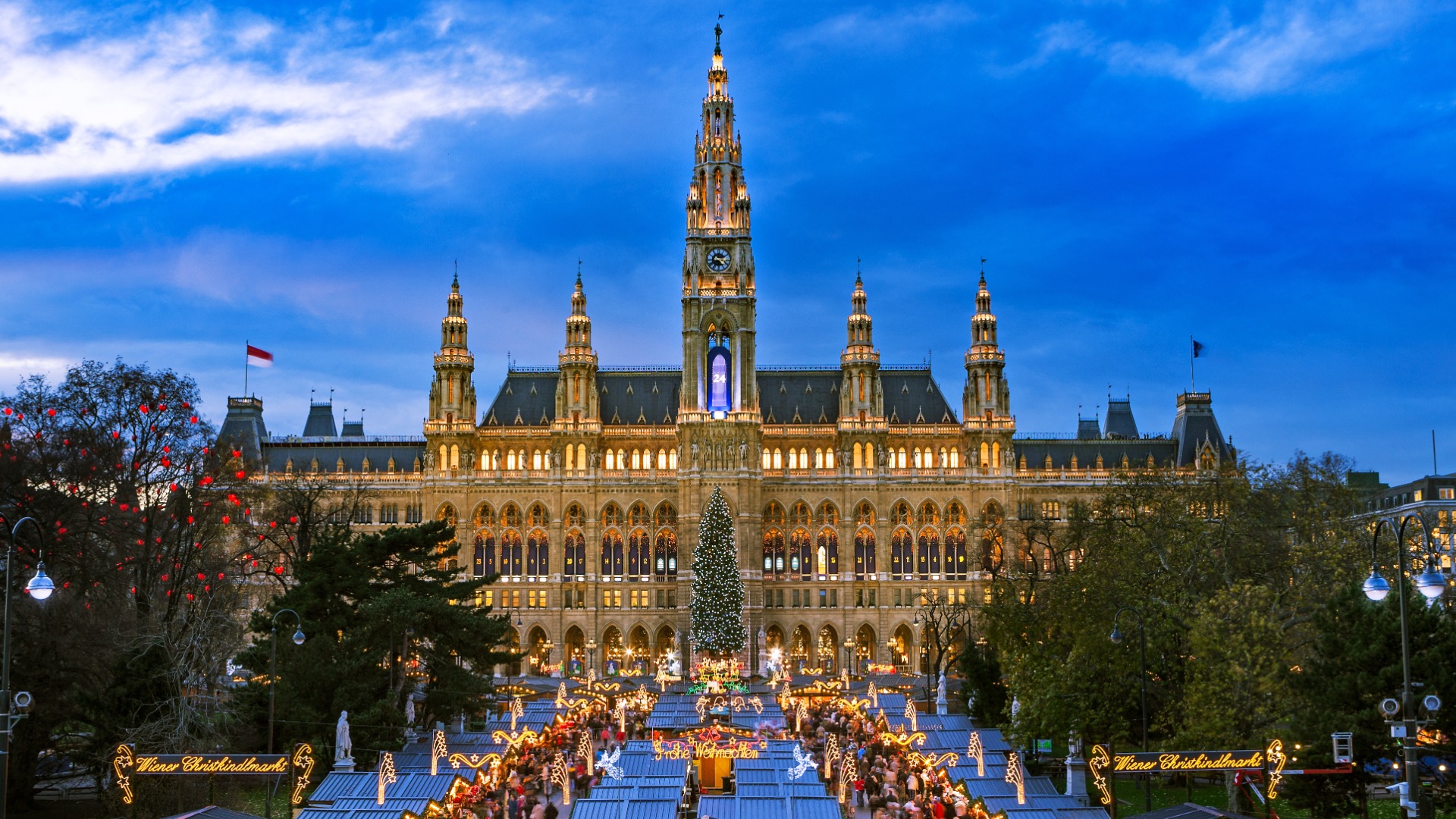 A panoramic view of the City Hall and the Christmas Market in front of it, illuminated for the festive season.