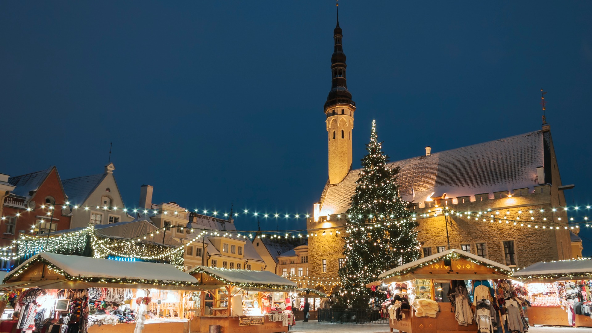 A bustling Christmas market in Tallinn filled with lights and souvenir stalls.