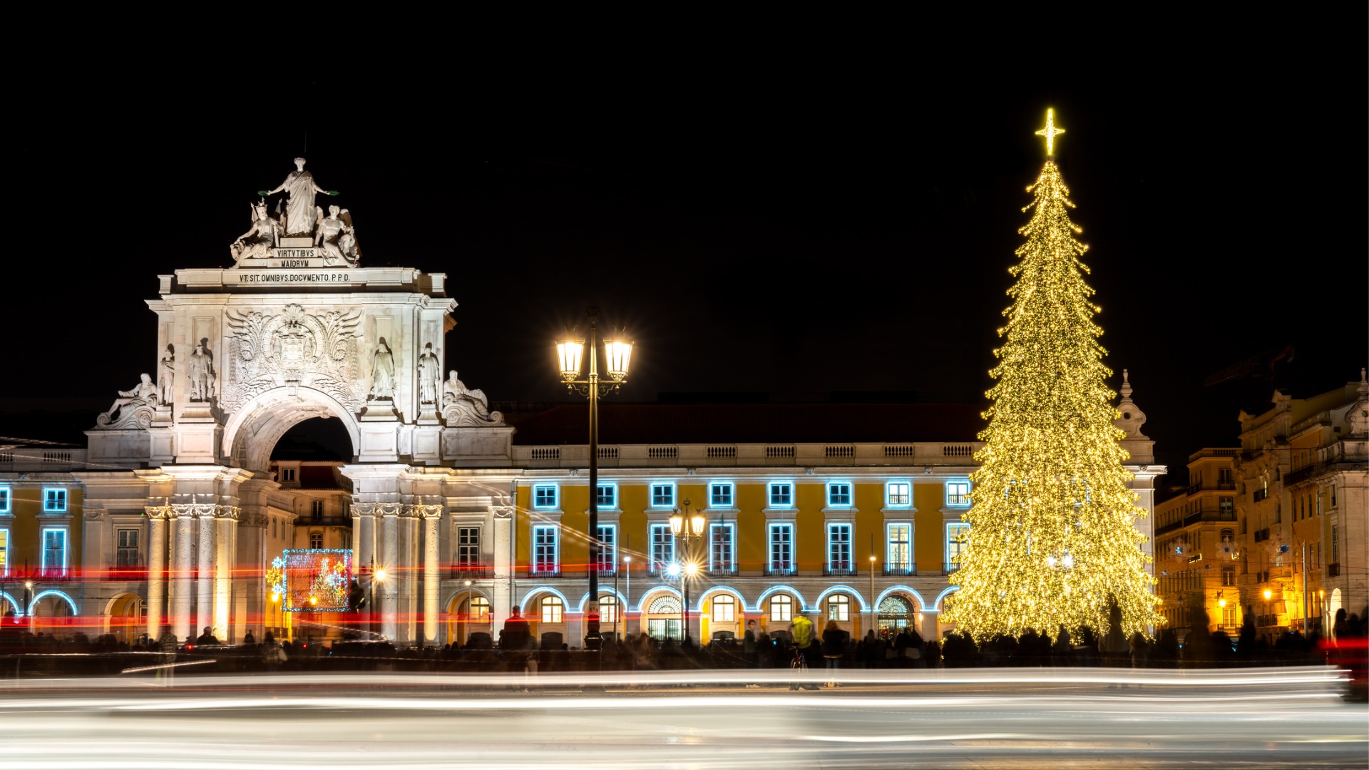 A nighttime view of Comércio Square, adorned with festive lights and a magnificent Christmas tree.