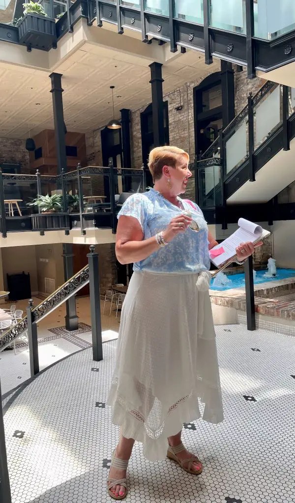 Woman in a baby blue blouse and white skirt conducting a food tour in Downtown Lexington, Kentucky.