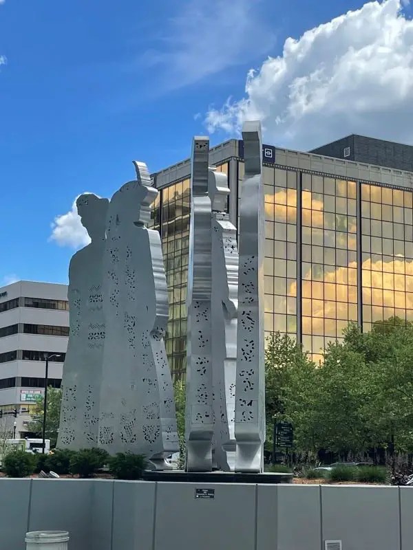 Metal sculpture featuring several outlines of women against a modern building in downtown Lexington. The Stand is a piece of public art and one of the few statues in the US honoring women.