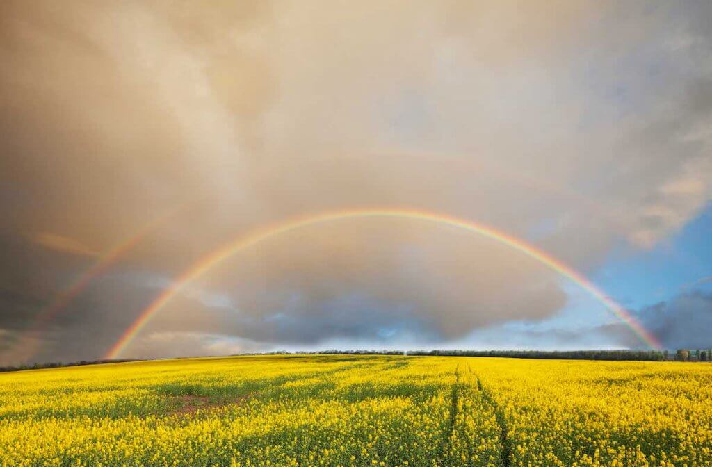 Hawaii in October features moments like a double rainbow. Image shows a double rainbow over a field in Hawaii.