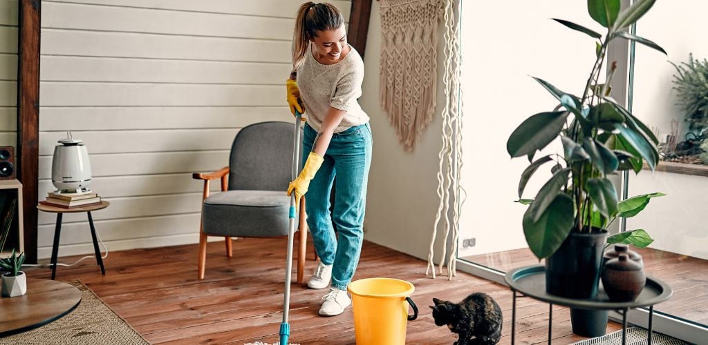 A young woman cleaning a floor while listening to music.