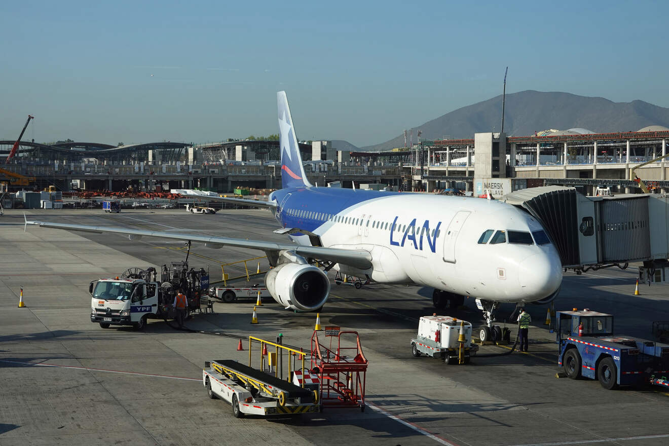 A LAN Airlines plane being serviced at Santiago International Airport amidst surrounding terminal construction.