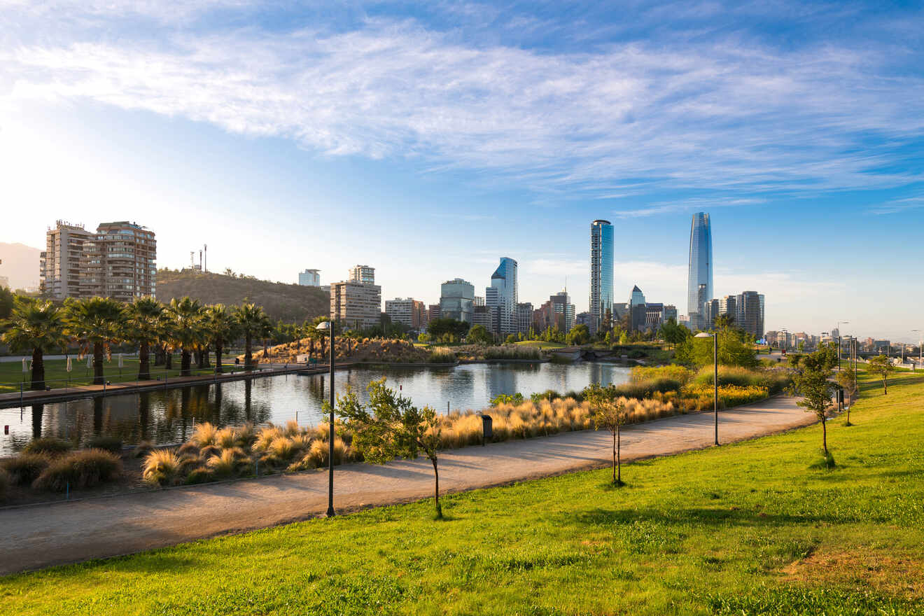 Santiago de Chile's modern skyline seen from a park featuring a serene pond and well-maintained greenery.