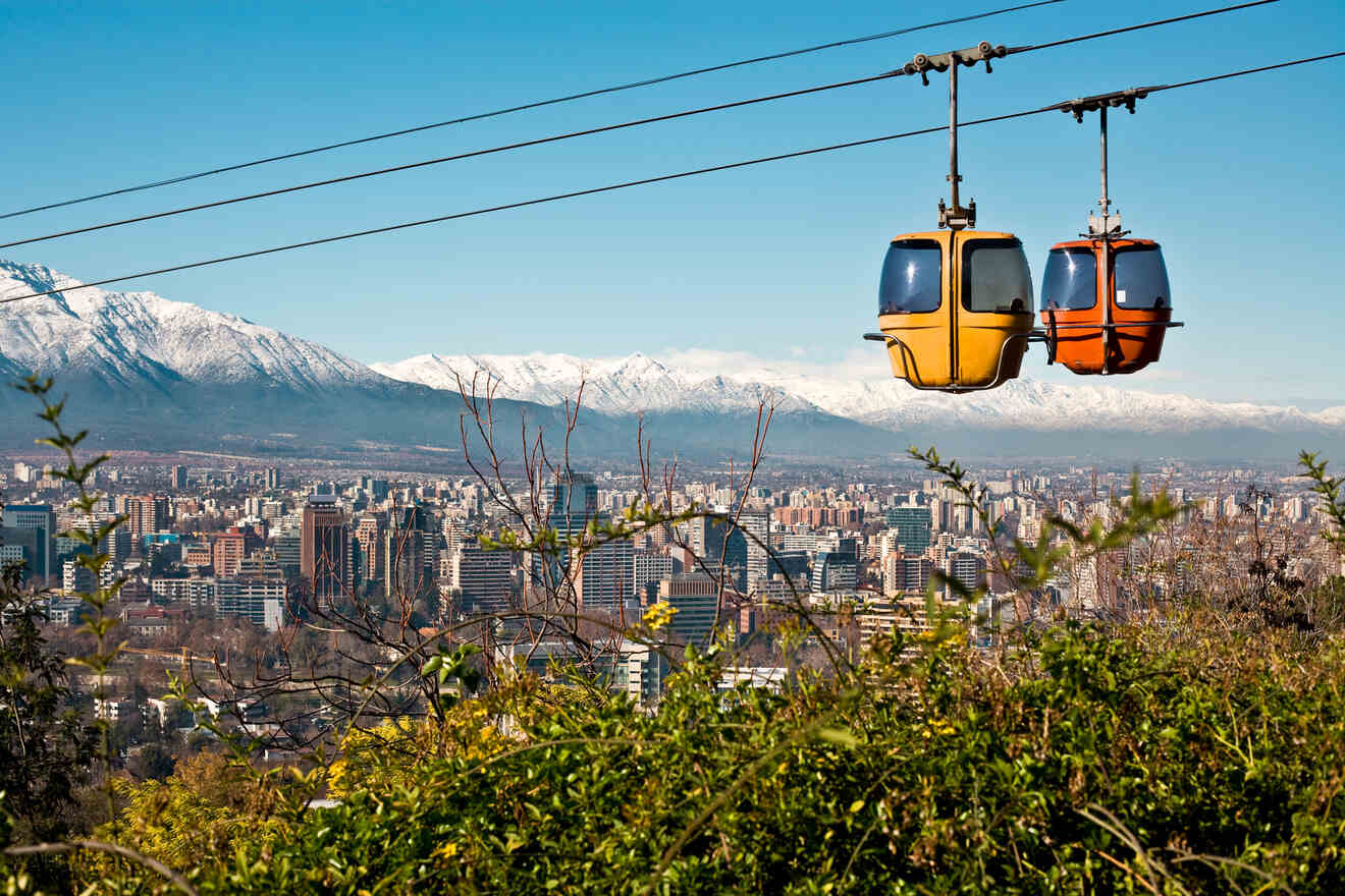 Two colorful cable cars suspended over Santiago de Chile, with the stunning cityscape and Andes Mountains in the backdrop.