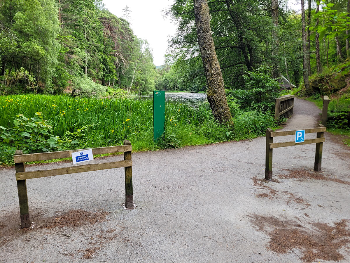 Two wooden posts marked with disabled parking signs next to the Loch Dunmore trail.