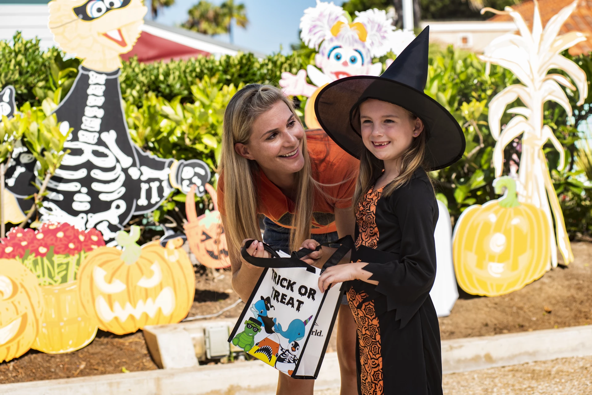 A young girl trick-or-treats with her mother.