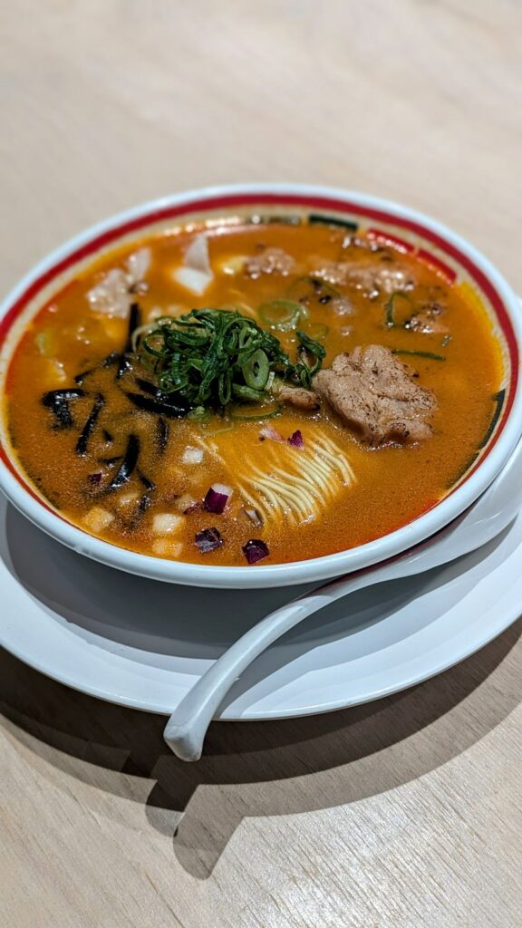 a large bowl of golden ramen with a large amount of noodles and soy meat at Vegan Bistro Jangara in Tokyo