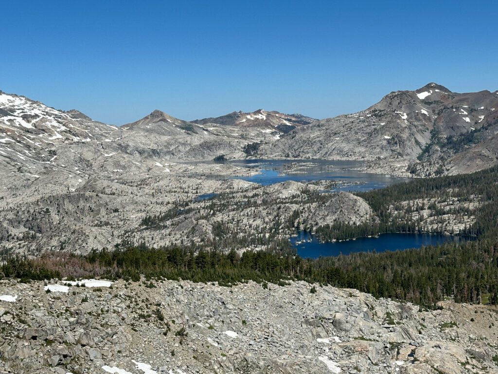 A view of Aloha Lake from Ralston Peak in California's Desolation Wilderness. Rocky mountains contrast with the deep blue water.