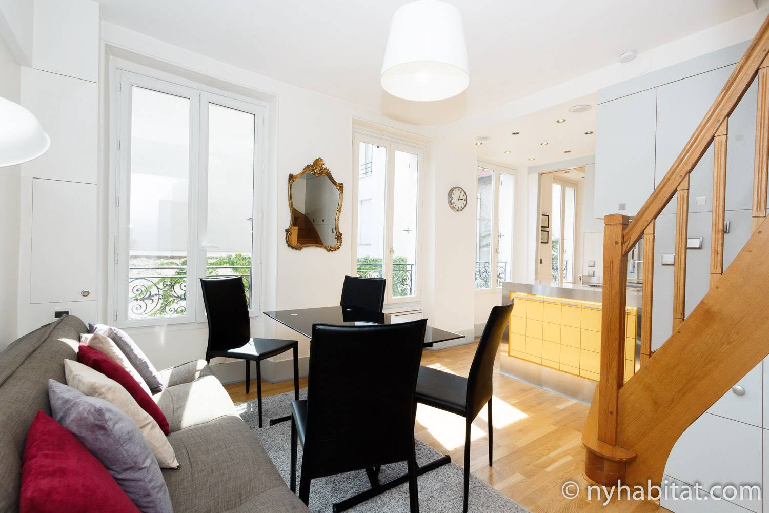 Living room of furnished apartment PA-4335 in Belleville, Paris, showcasing numerous windows and stairs leading to the upper level.