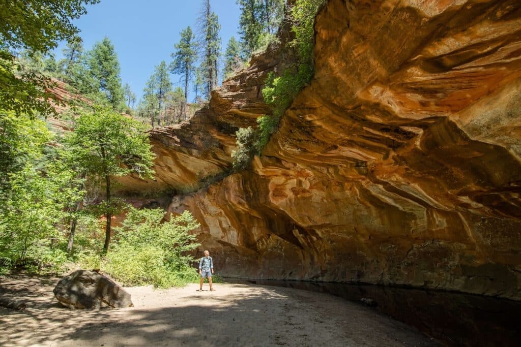 Man walking under red rock overhang on the West Fork Trail in Sedona