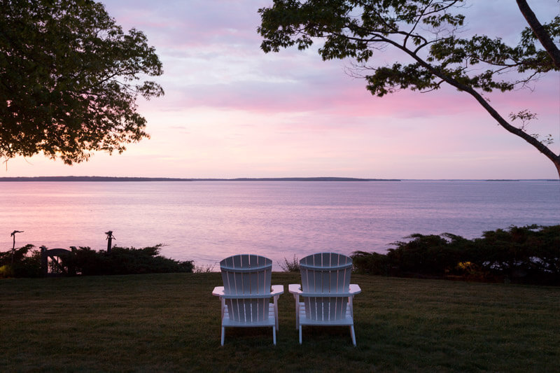 Two chairs facing the sunrise over the Maine coast