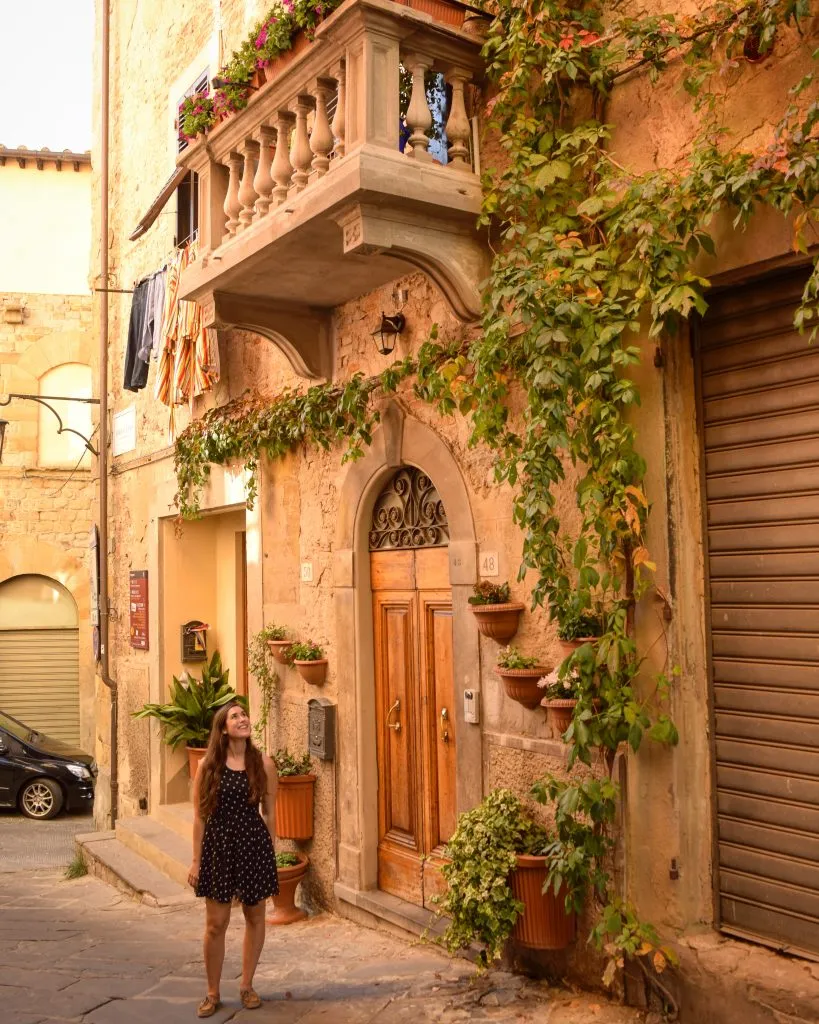 Kate Storm standing in front of a picturesque door and balcony in Arezzo, Italy