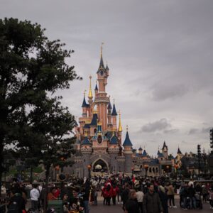 A castle bustling with visitors in front of it.