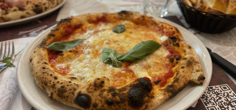 Delicious pizza garnished with a basil leaf.